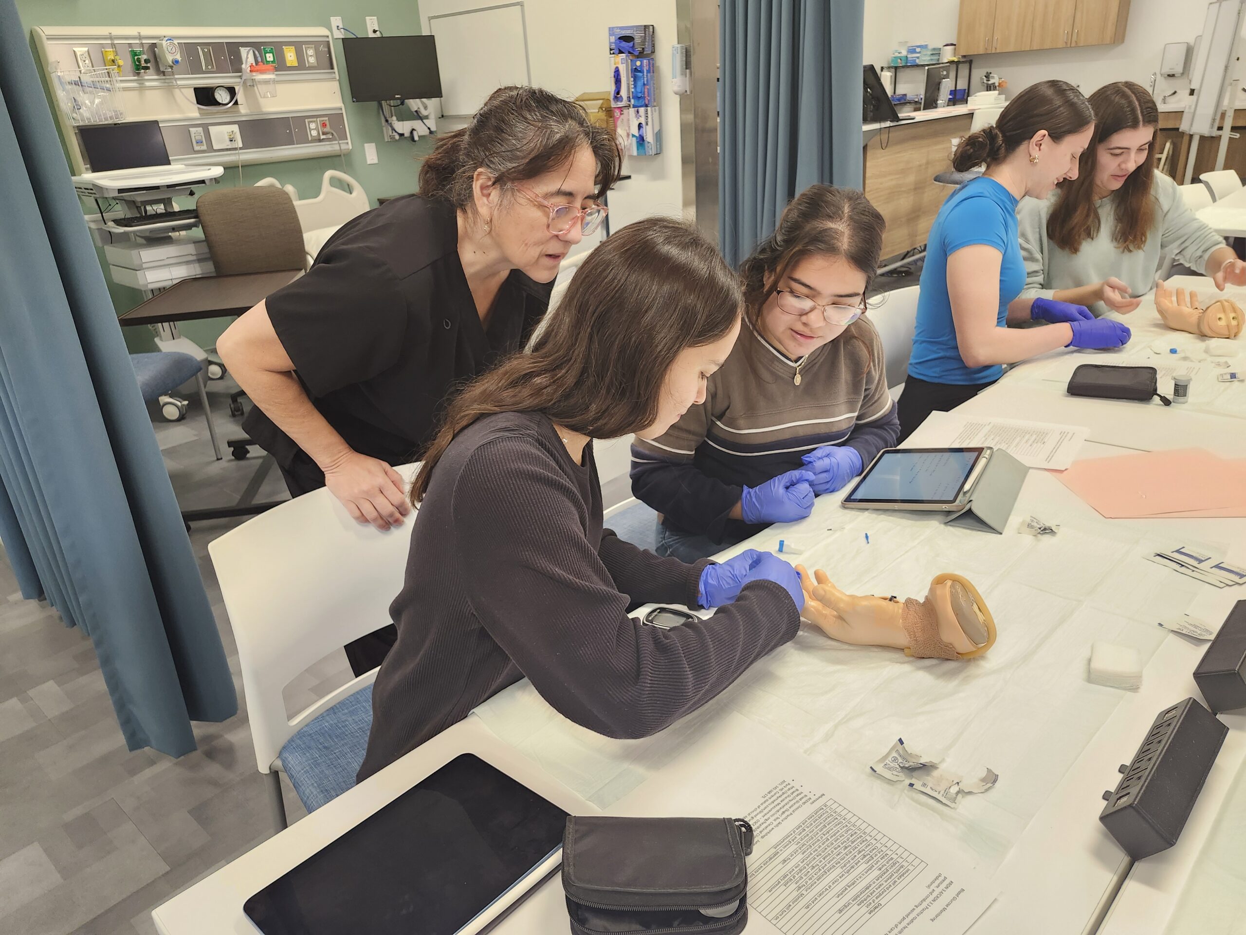 Students in a lab looking over a fake hand.