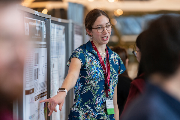 a student explains her work to onlookers at the Nutrition Symposium